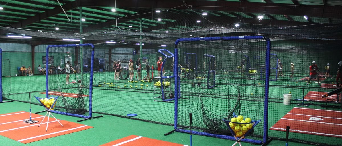 A wide view across the facility floor showing multiple batting lanes and cages in use