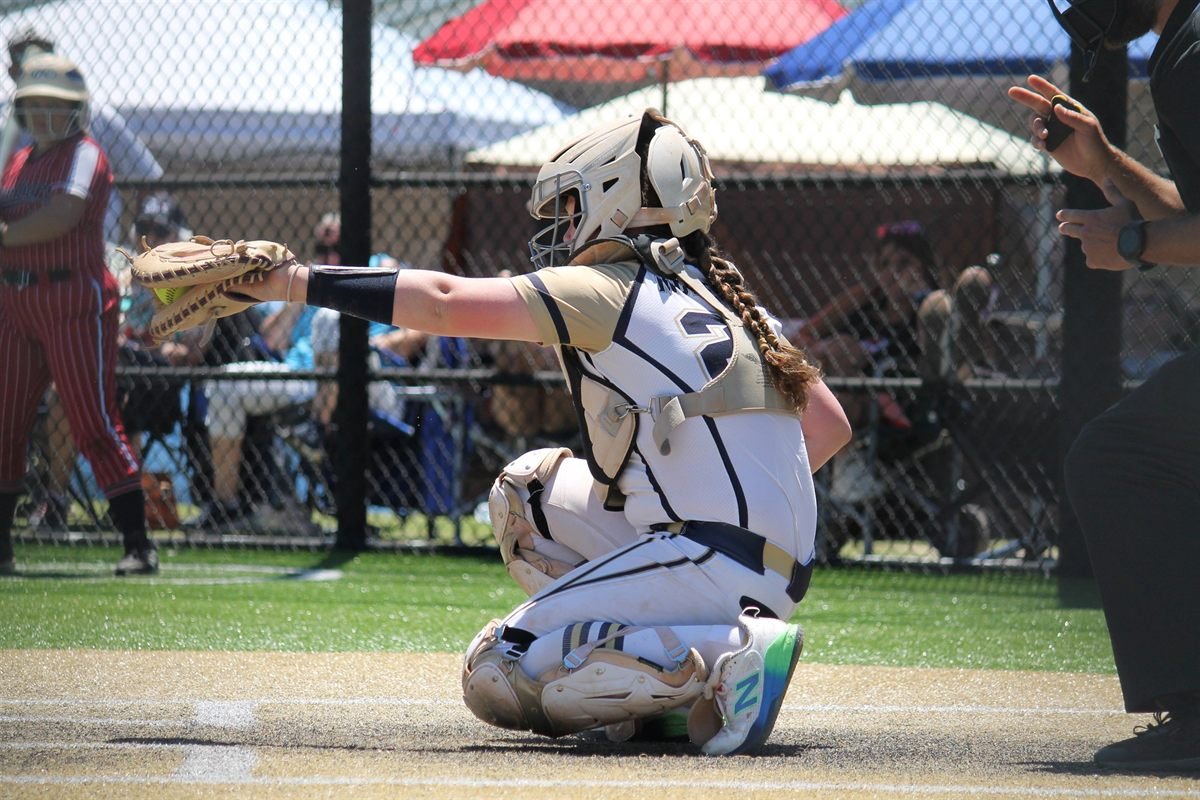A Fury catcher in full gear, glove extended to receive a pitch at the plate