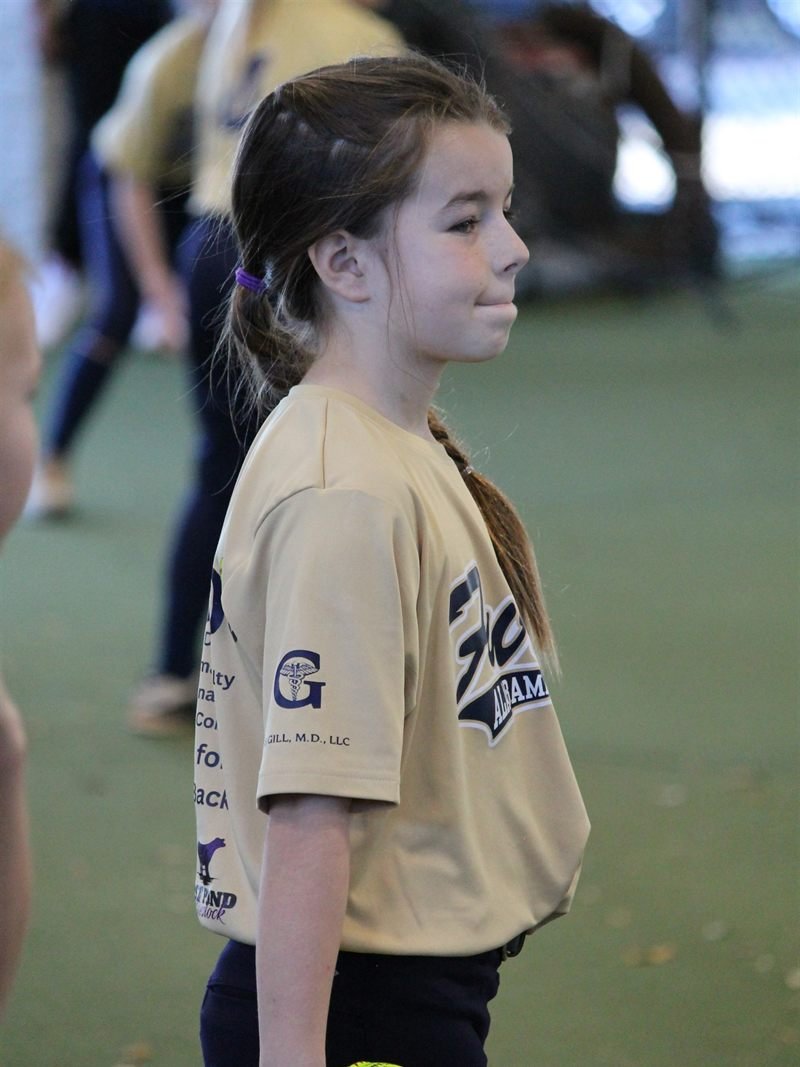 A young Fury player holding a softball at her first practice